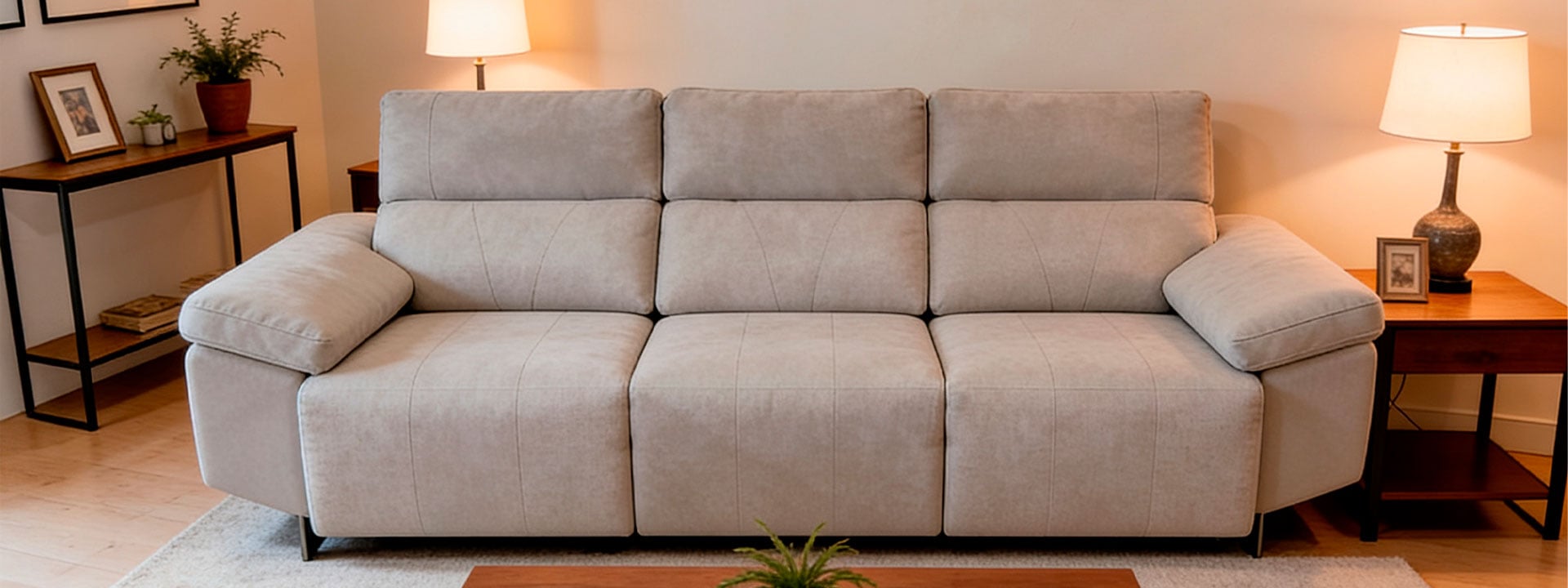 Sofá de tela gris en sala moderna con iluminación cálida y decoración elegante.